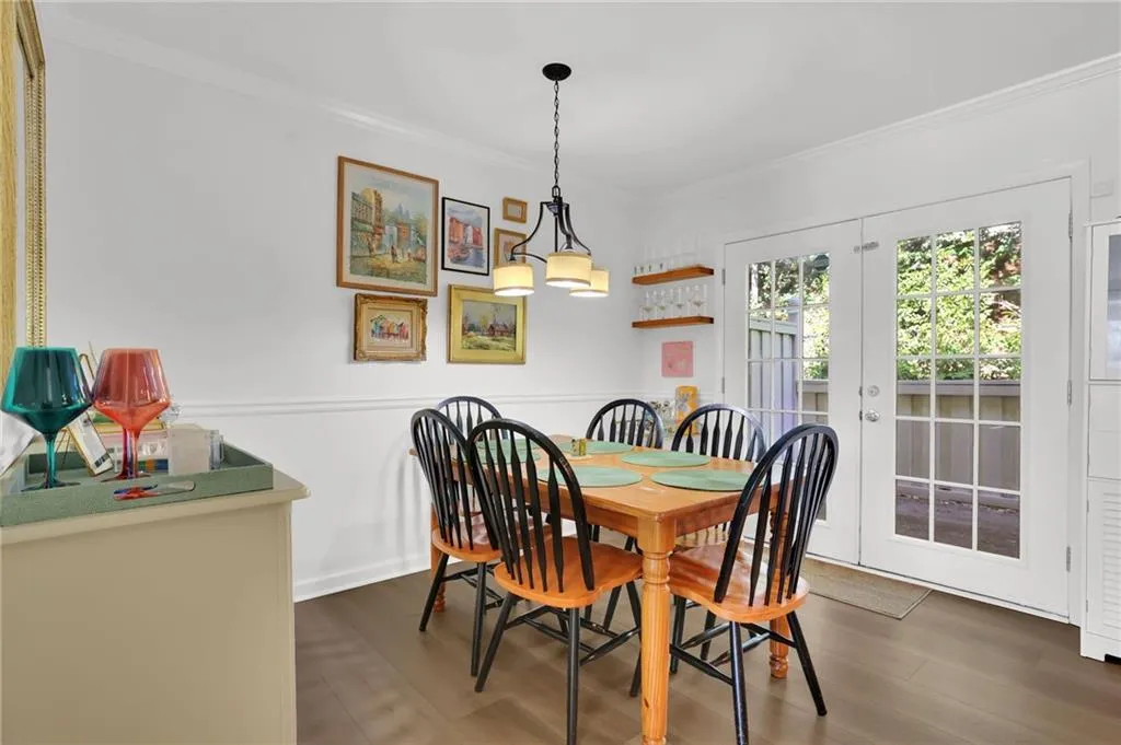 Dining space with french doors, crown molding, and dark wood-style flooring