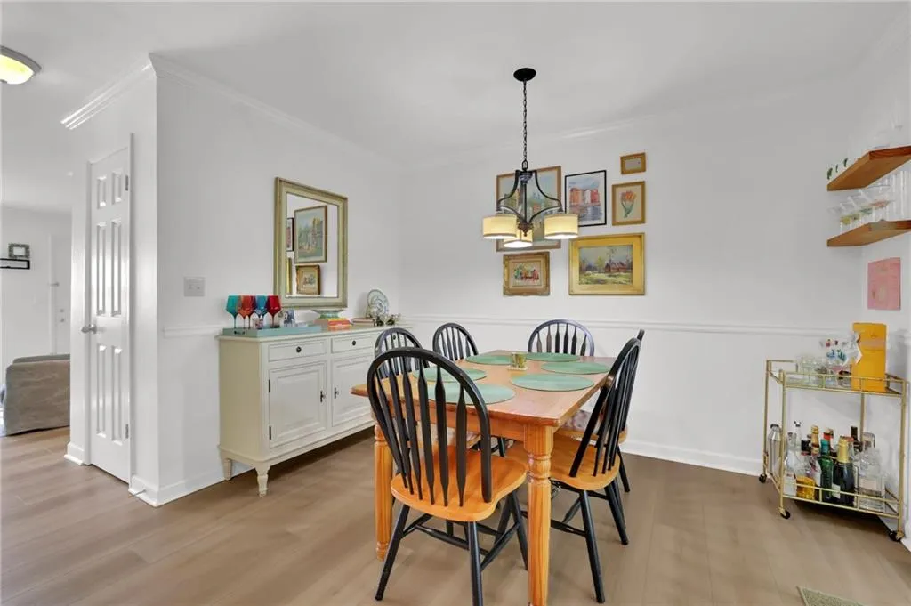 Dining space with light wood-style flooring, crown molding, and a chandelier