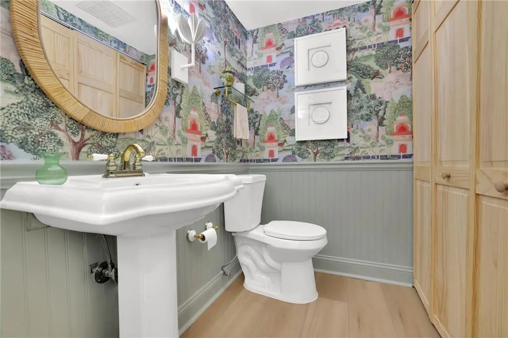Bathroom with wainscoting, wallpapered walls, and wood finished floors