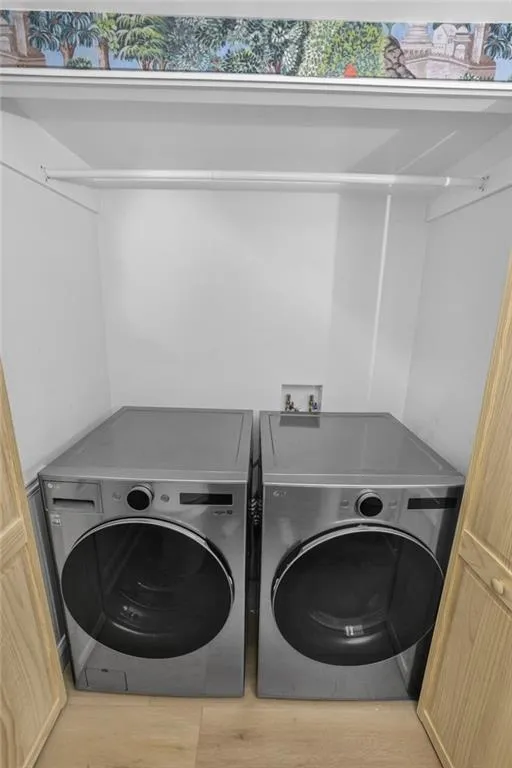 Laundry room with independent washer and dryer and wood finished floors