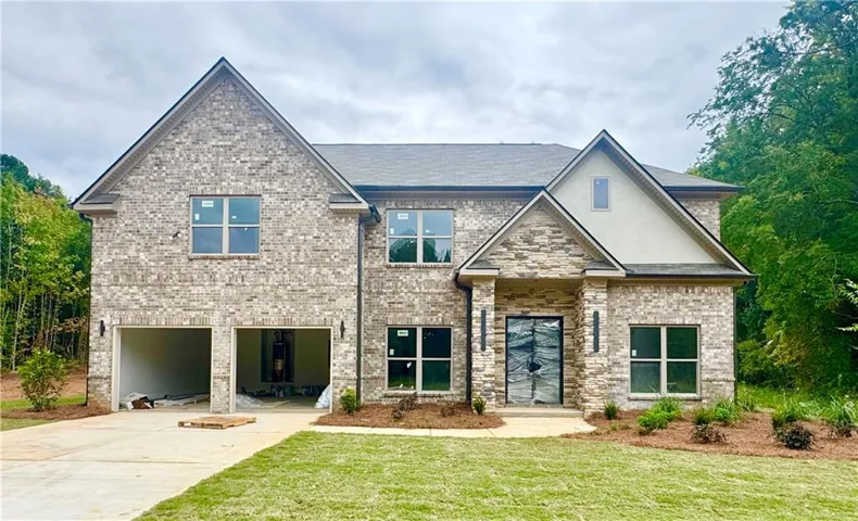 Brick and stone facade, two-car garage, established front landscaping, asphalt shingle roof, and a prominent front entrance