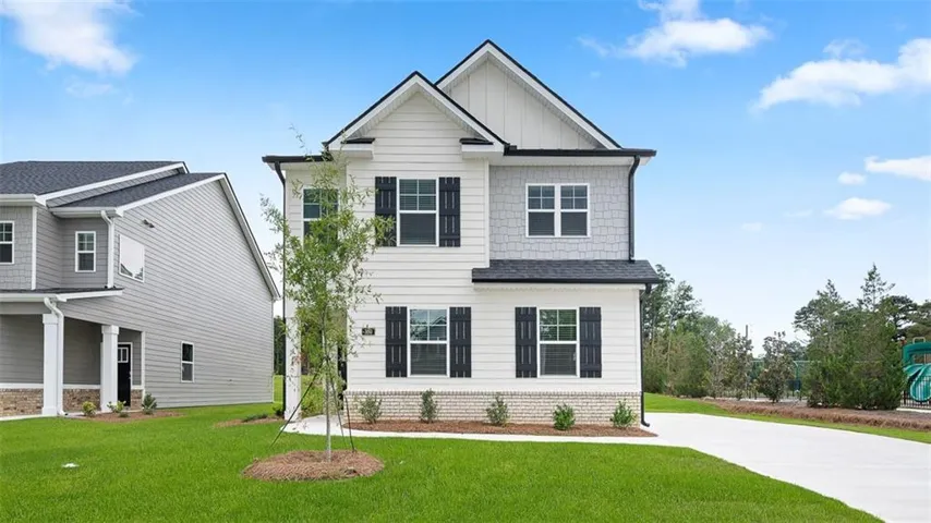 Two-story residence featuring a combination of horizontal siding and shake siding, dark shingle roof, black window shutters, and a concrete driveway