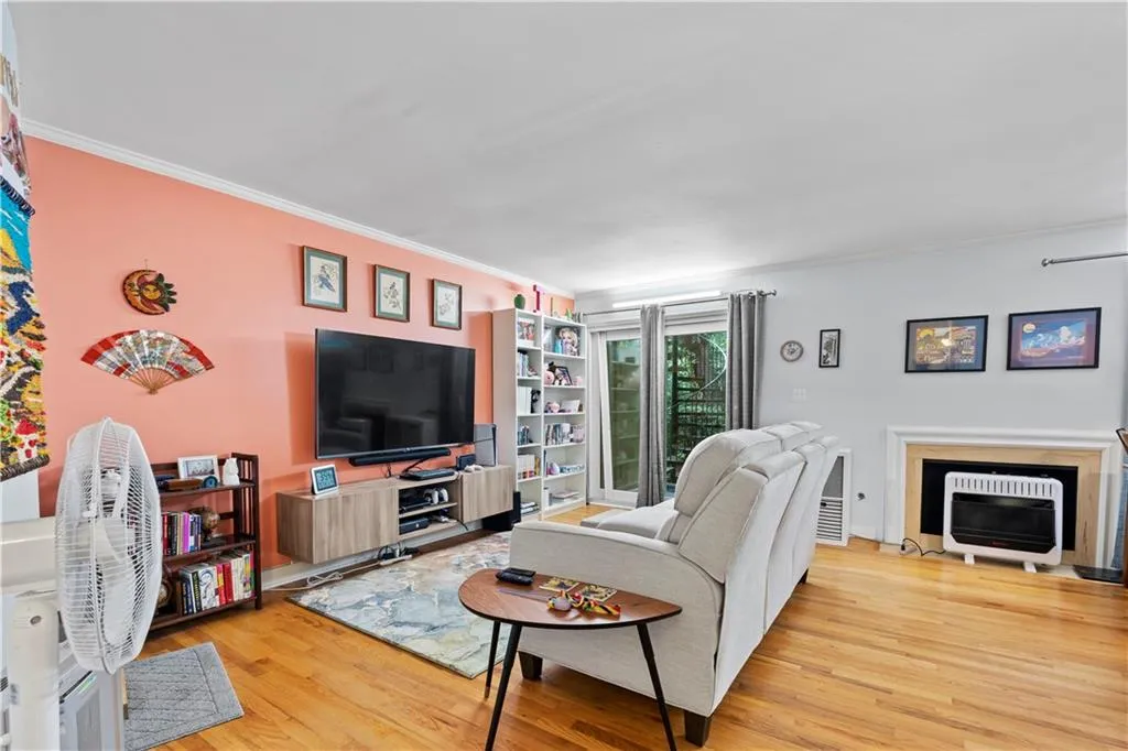 Living room featuring heating unit, light wood-style floors, and ornamental molding