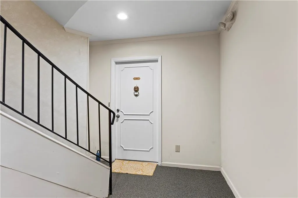 Carpeted foyer entrance with stairs and ornamental molding