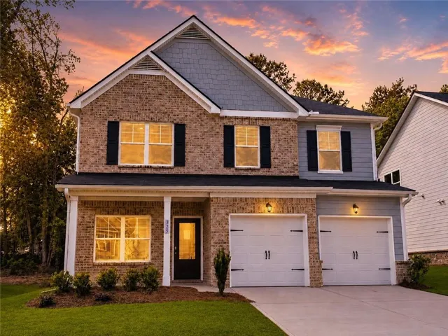 Elegant brick-front home with warm evening glow, lush curb appeal, spacious design, and a serene sunset backdrop. Move-in ready and beautifully inviting.
