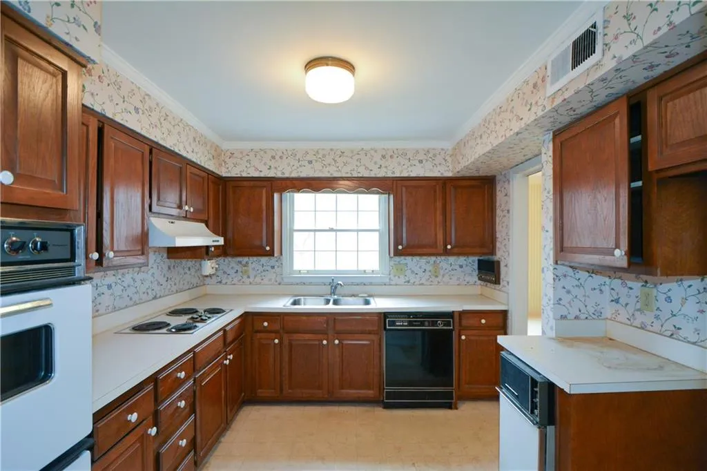 Kitchen with ornamental molding, light tile floors, white appliances, and sink