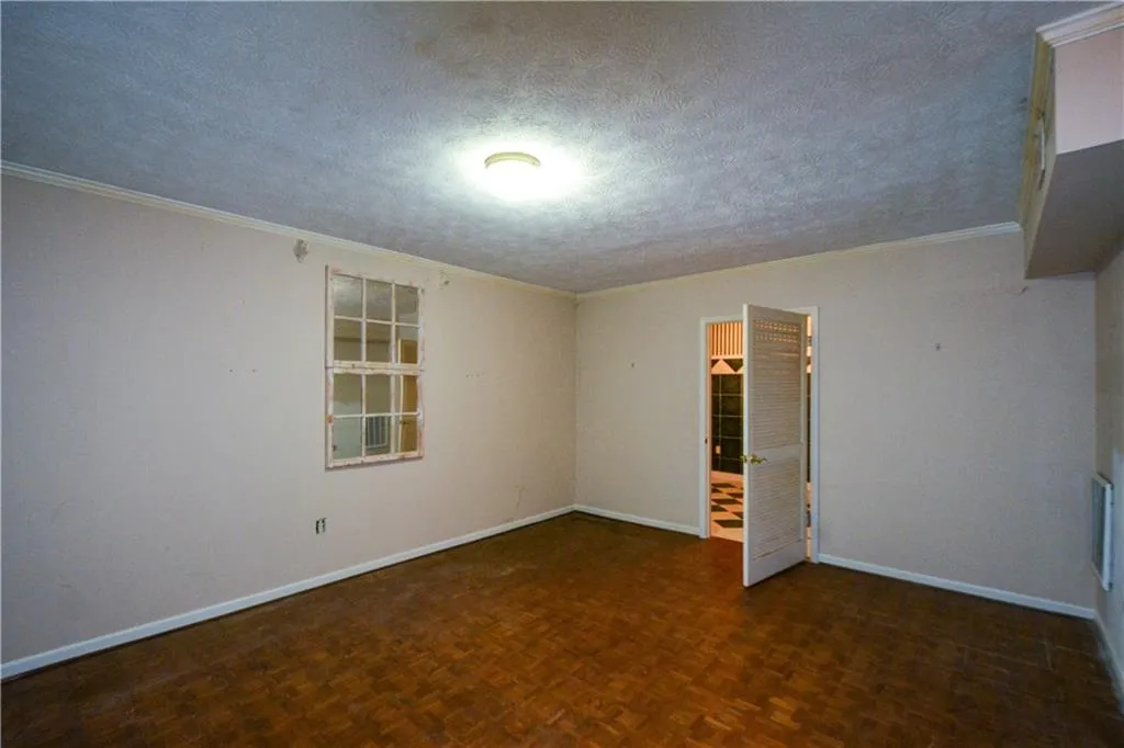 Spare room featuring dark parquet floors and a textured ceiling