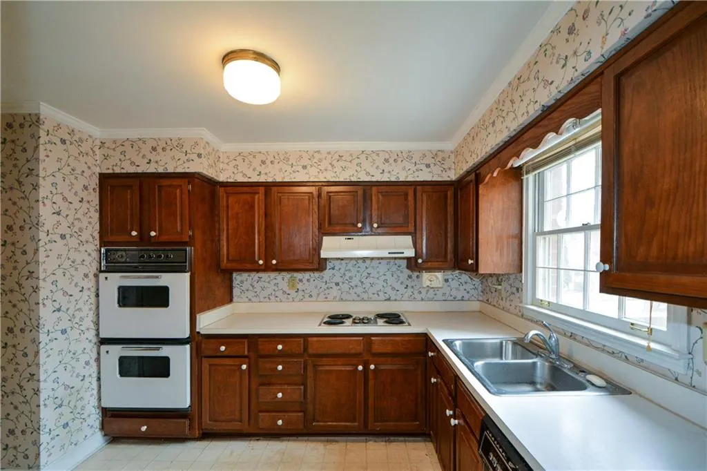 Kitchen with sink, white appliances, crown molding, and light tile floors