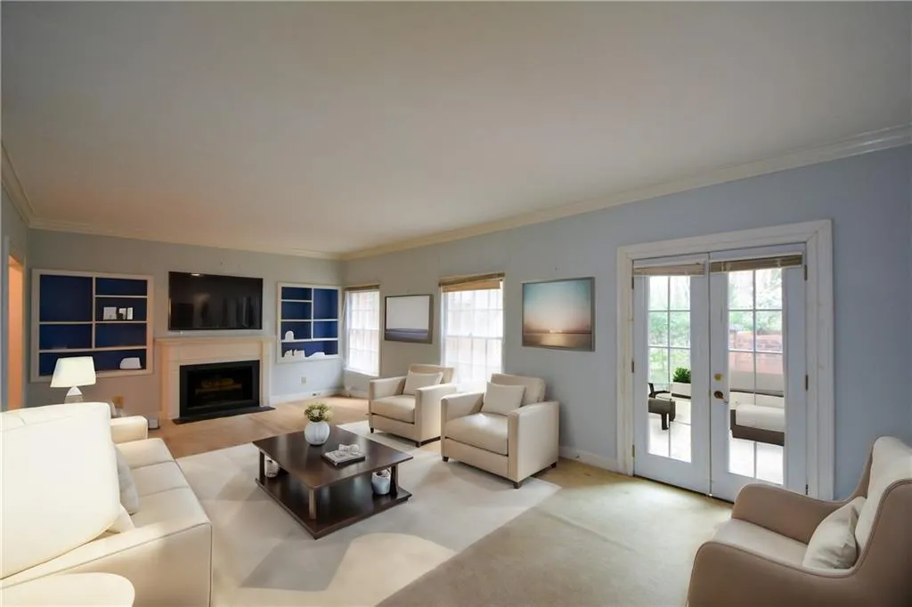 Living room featuring light colored carpet, built in features, french doors, and crown molding