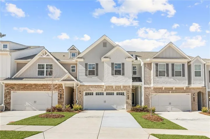 Modern townhome-style residences featuring brick and siding exteriors, dormer windows, and attached two-car garages