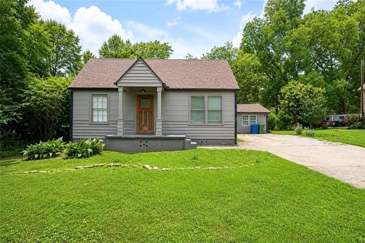 Gable roofline with shingle siding, wood-paneled front door, and a covered porch