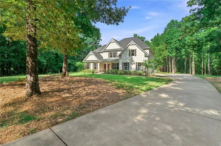 Two-story residence with a light-toned facade, dark-shingled roof, and dark shutters