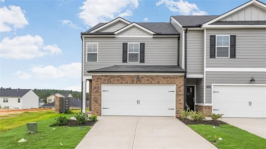 Siding exterior with brick accents, black shutters, and a two-car garage
