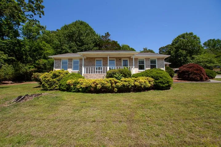Brick exterior with white window trim and a covered front porch featuring a white railing