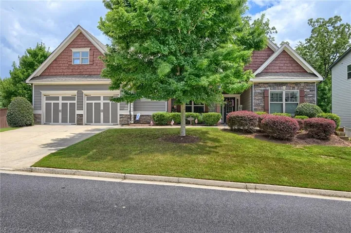 Siding and stone facade with a two-car garage and a concrete driveway