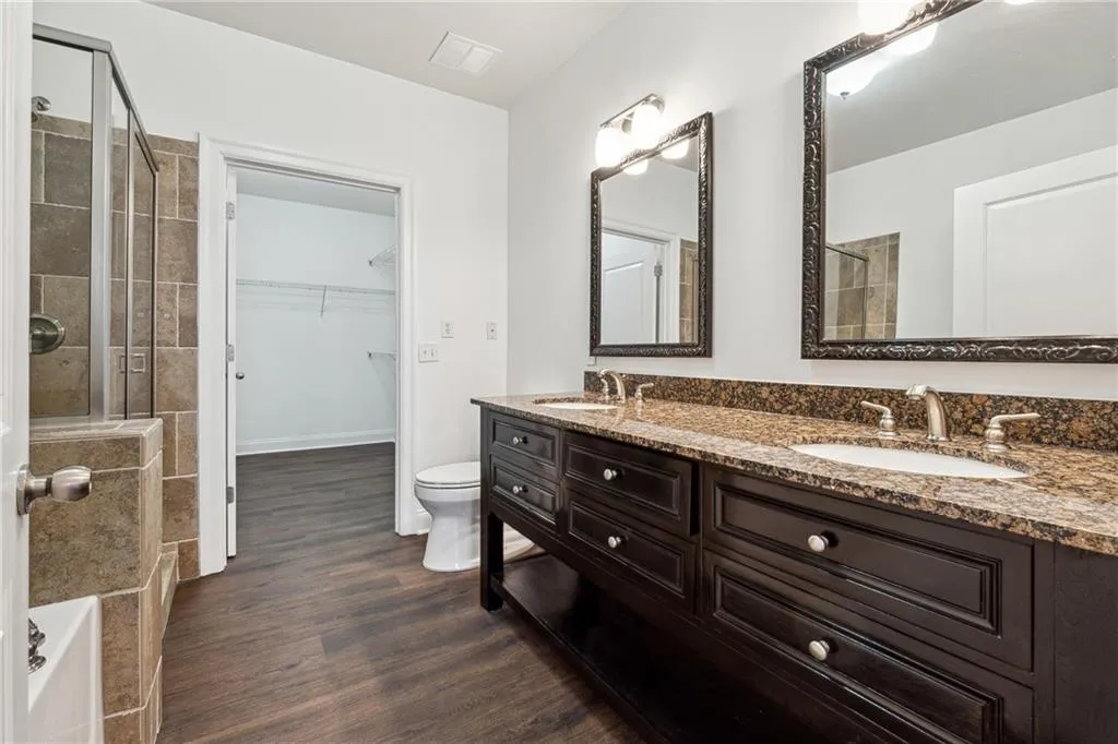 Bathroom with wood finished floors, tiled shower, and a sink