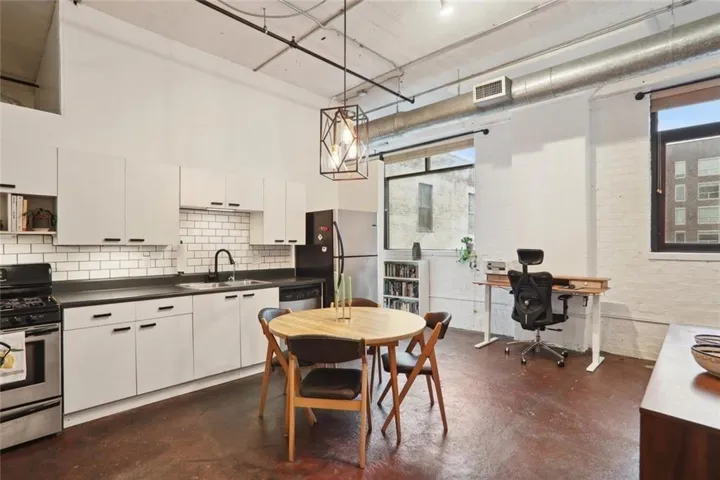 Modern kitchen featuring white cabinetry, subway tile backsplash, and dark countertops
