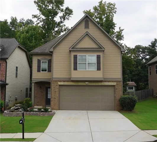 Two-story exterior featuring brick and siding finishes, a two-car garage, and a concrete driveway