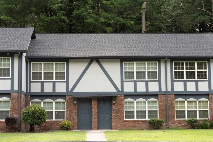Brick and siding exterior with dark gray trim, featuring multiple pane windows and a shingled roof