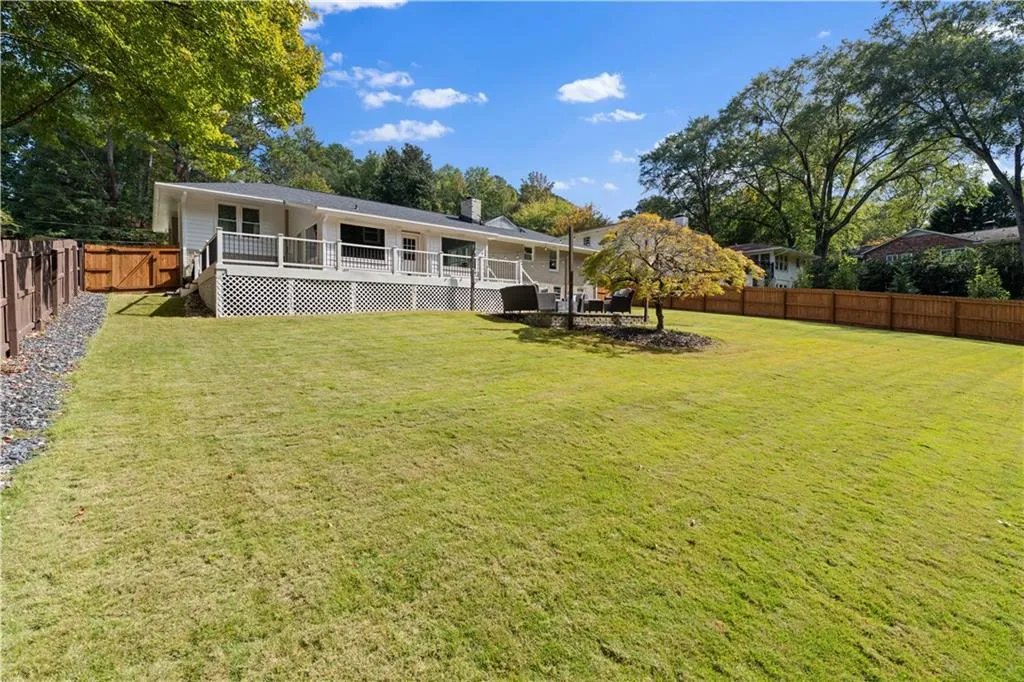 Rear view of property with a lawn and a deck