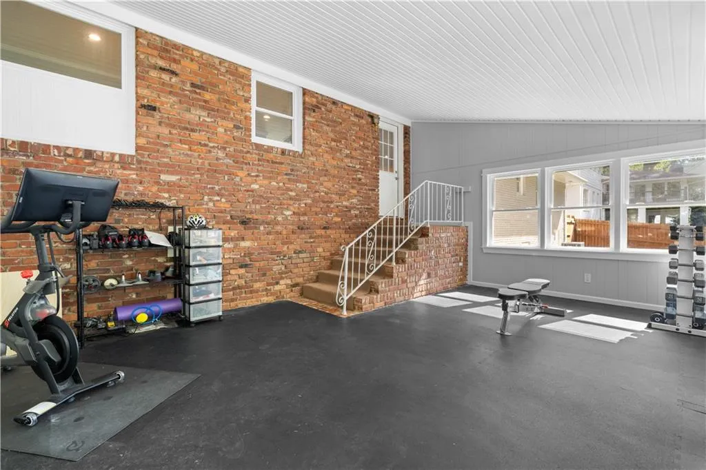 Exercise room featuring lofted ceiling and brick wall
