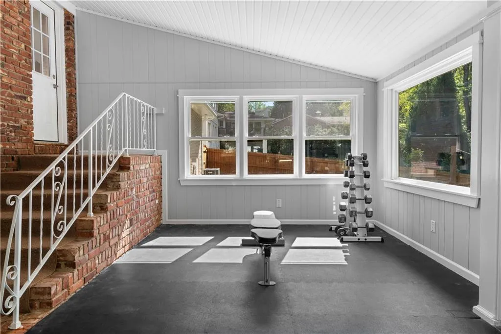 Exercise room with vaulted ceiling and brick wall