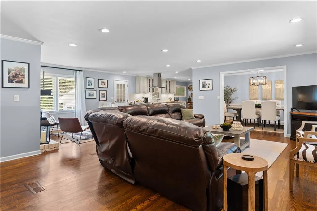 Living room featuring a notable chandelier, dark hardwood / wood-style floors, and crown molding