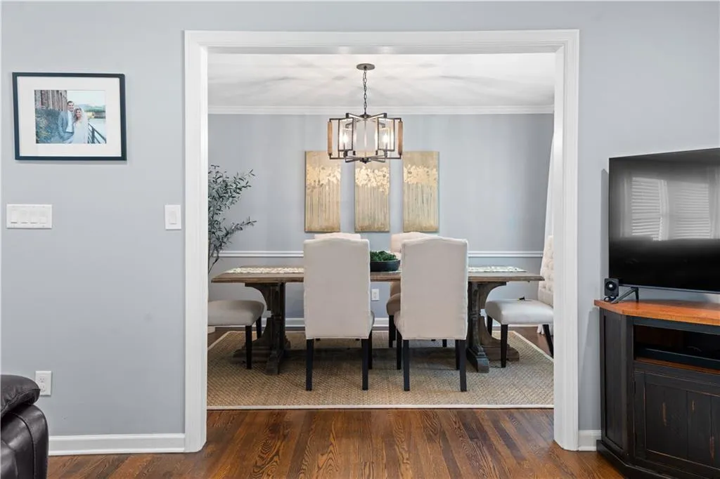Dining room featuring dark wood-type flooring, a chandelier, and ornamental molding