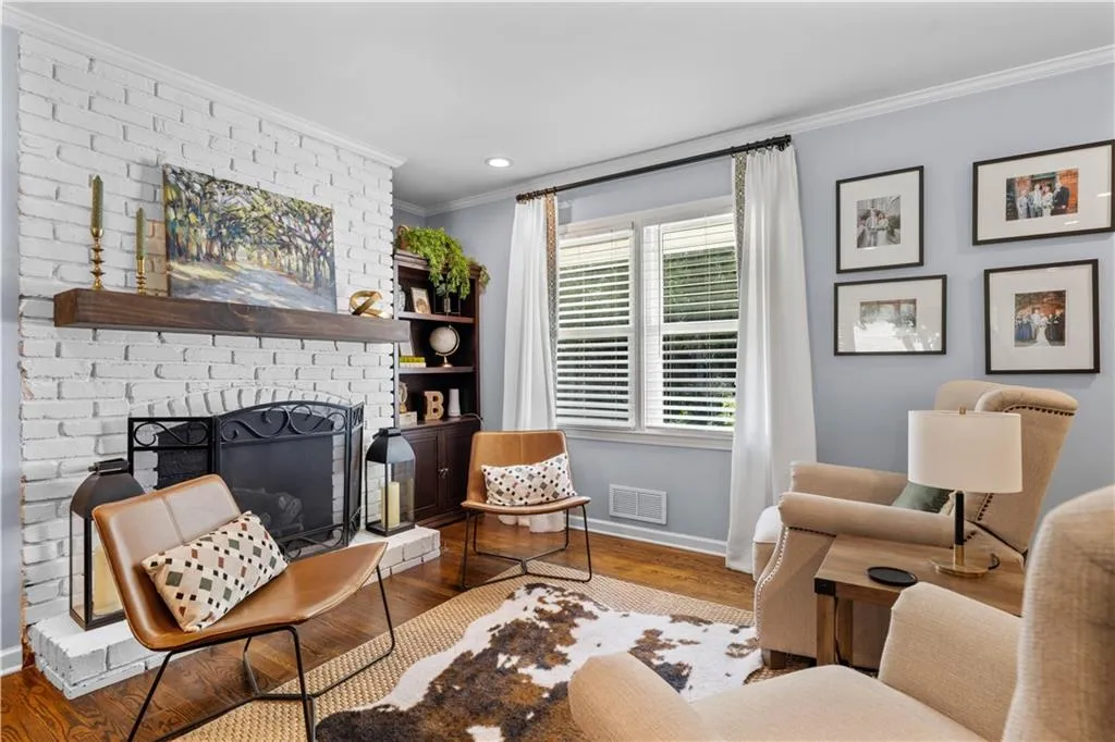 Living room featuring hardwood / wood-style flooring, crown molding, and a brick fireplace