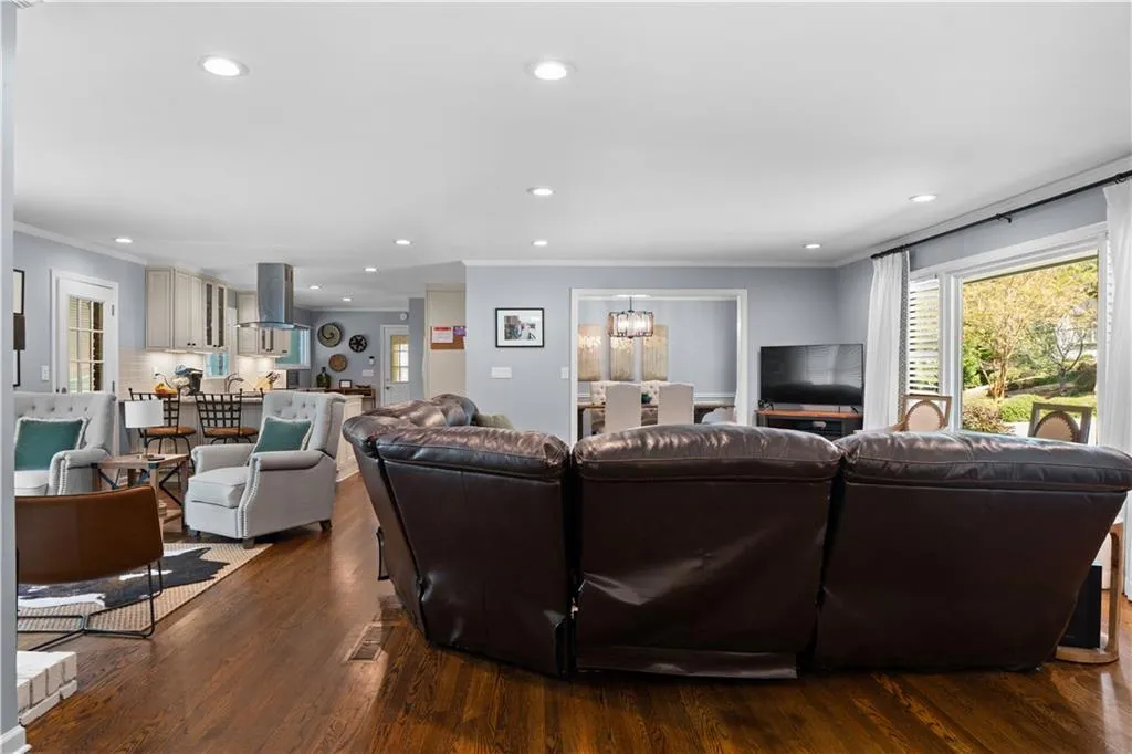 Living room featuring dark wood-type flooring, a chandelier, and ornamental molding
