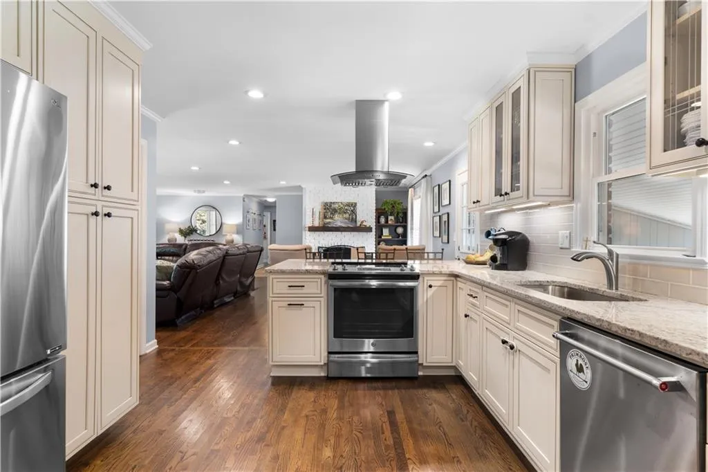 Kitchen with sink, appliances with stainless steel finishes, ornamental molding, dark hardwood / wood-style floors, and island range hood