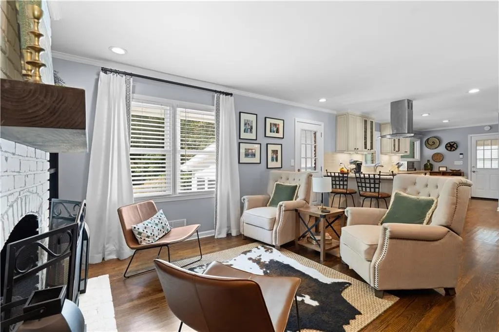 Living room featuring a brick fireplace, wood-type flooring, plenty of natural light, and ornamental molding