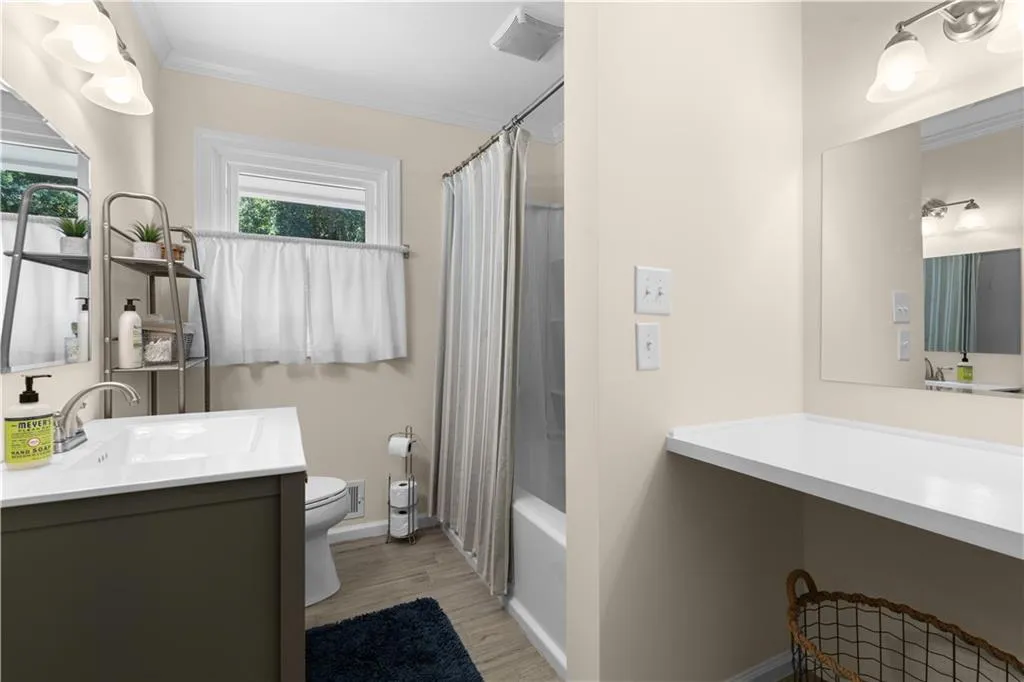 Full bathroom featuring shower / tub combo, ornamental molding, hardwood / wood-style floors, vanity, and toilet