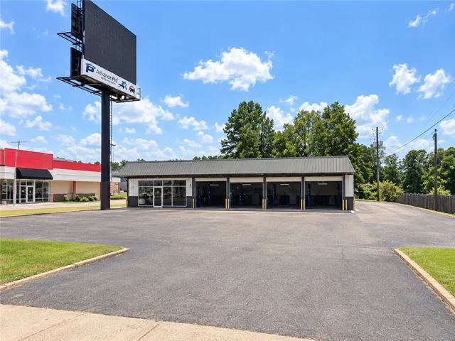Building featuring a metal roof, multiple bay doors, and a large paved lot