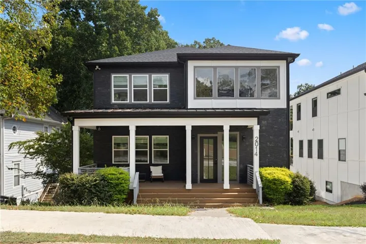 Contemporary exterior featuring dark brick, white trim, a covered front porch with white columns, and an upper-level window bank