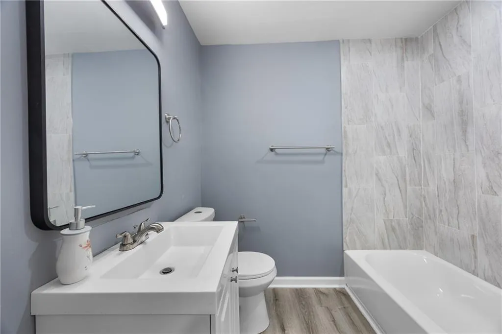 Hall bathroom with shower / tub combination, vanity, toilet, and hardwood / wood-style floors