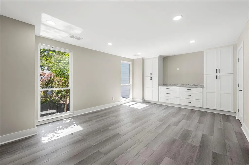 Primary bedroom with custom closet systems with room for a wall mount tv, Luxurious plank flooring and plenty of sunlight.