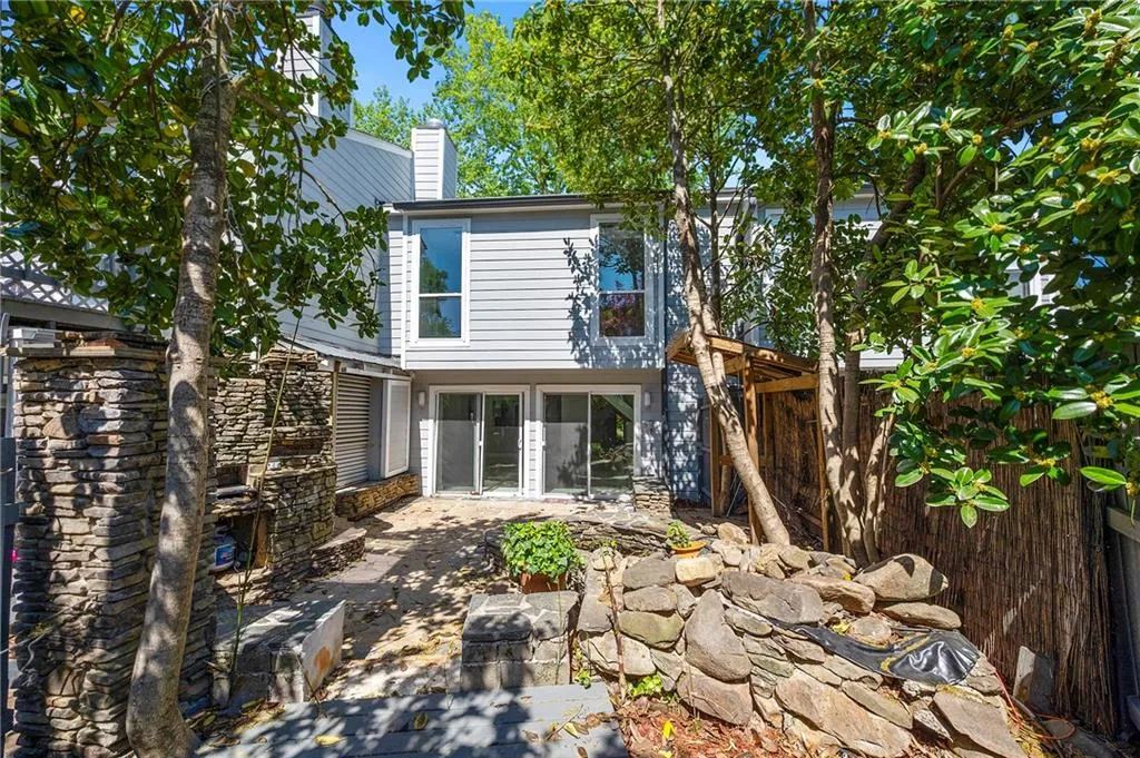 Back of property featuring a patio with pond and stone fireplace