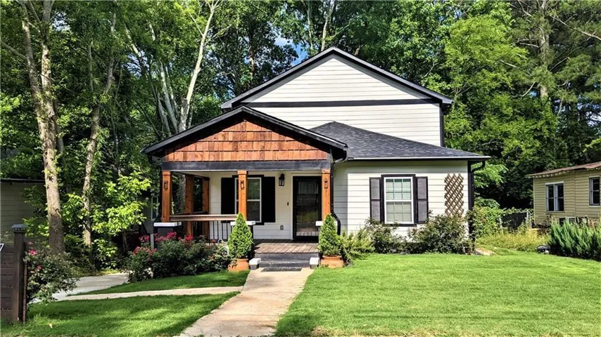 Charming cottage-style home featuring a welcoming front porch with wood-finish siding and black metal roof accents