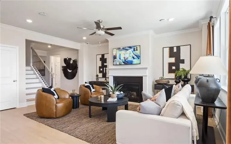 Living area featuring crown molding, stairs, wood finished floors, and a glass covered fireplace