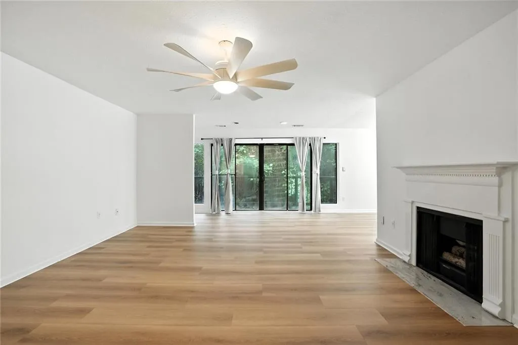 Unfurnished living room with light wood-style flooring, a fireplace with flush hearth, and ceiling fan