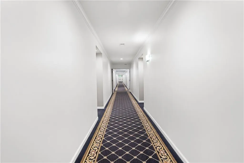 Corridor with crown molding and baseboards
