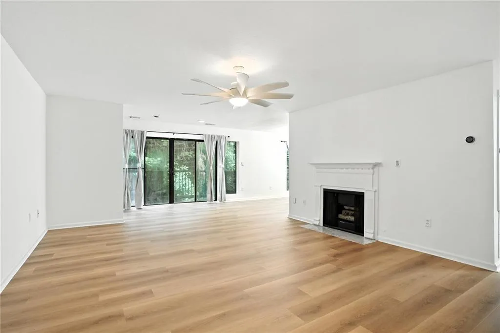 Unfurnished living room featuring a fireplace with flush hearth, light wood-type flooring, and a ceiling fan