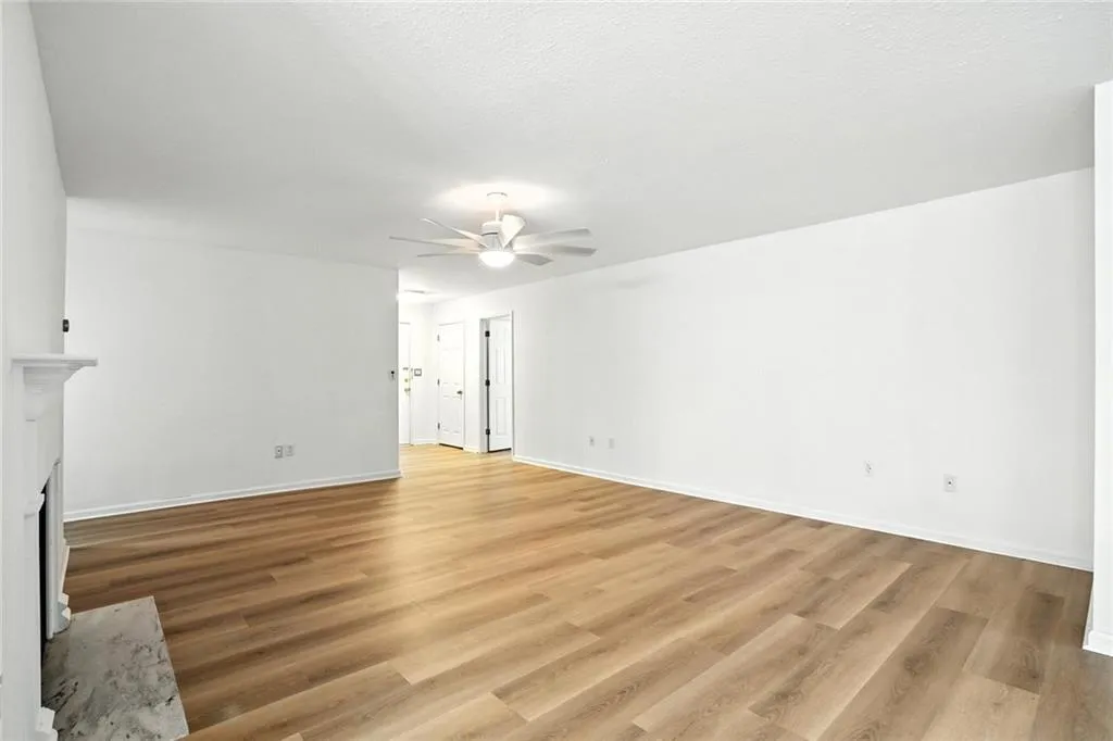 Unfurnished living room with light wood-type flooring, a fireplace, a ceiling fan, and a textured ceiling