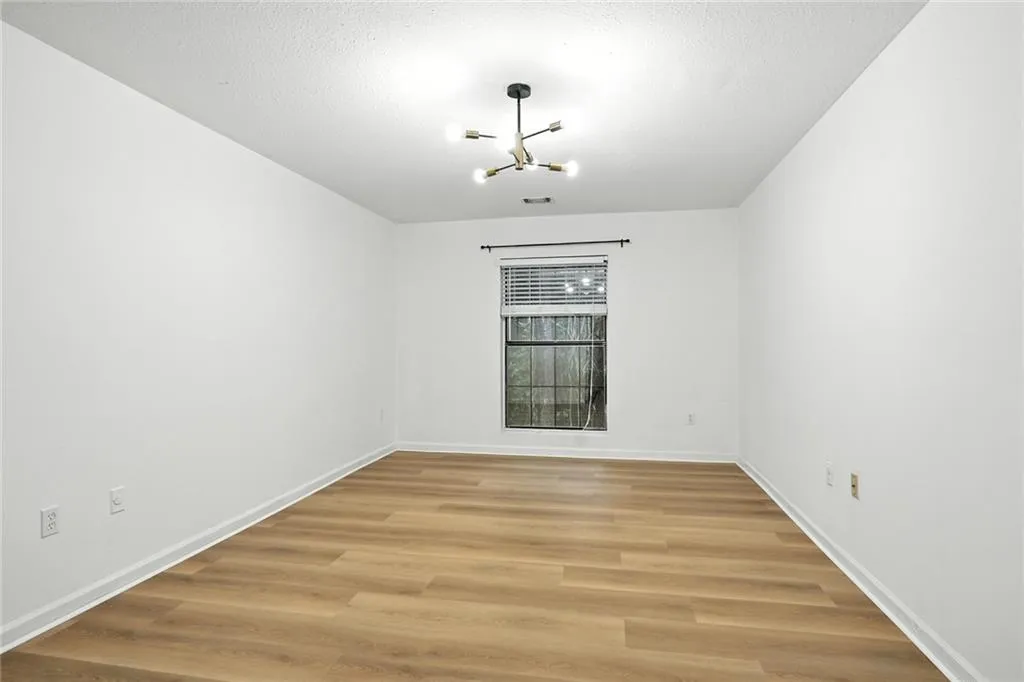 Unfurnished dining area featuring light wood-style flooring, a chandelier, and a textured ceiling