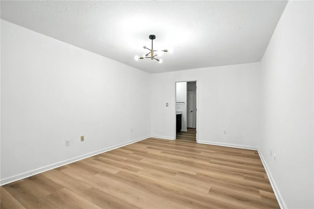 Unfurnished bedroom featuring a chandelier, light wood finished floors, and a textured ceiling