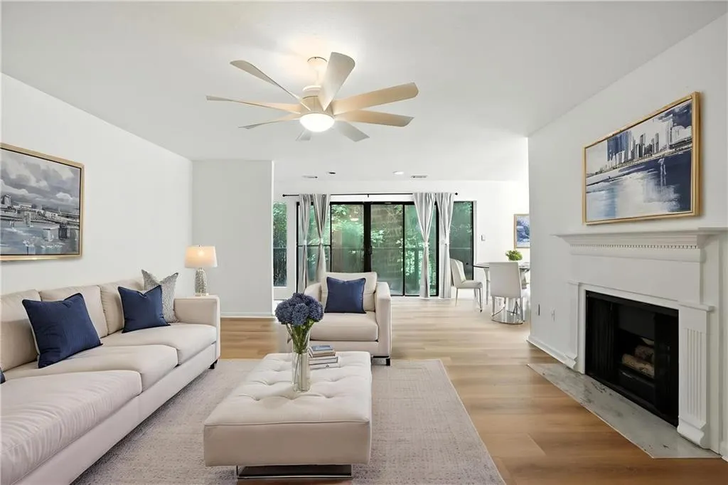 Living area with light wood-type flooring, a fireplace with flush hearth, and a ceiling fan