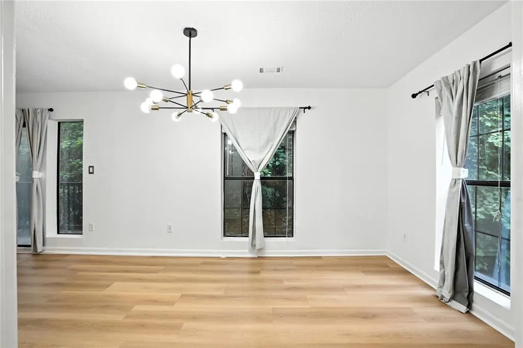Empty room with light wood-style floors and a chandelier