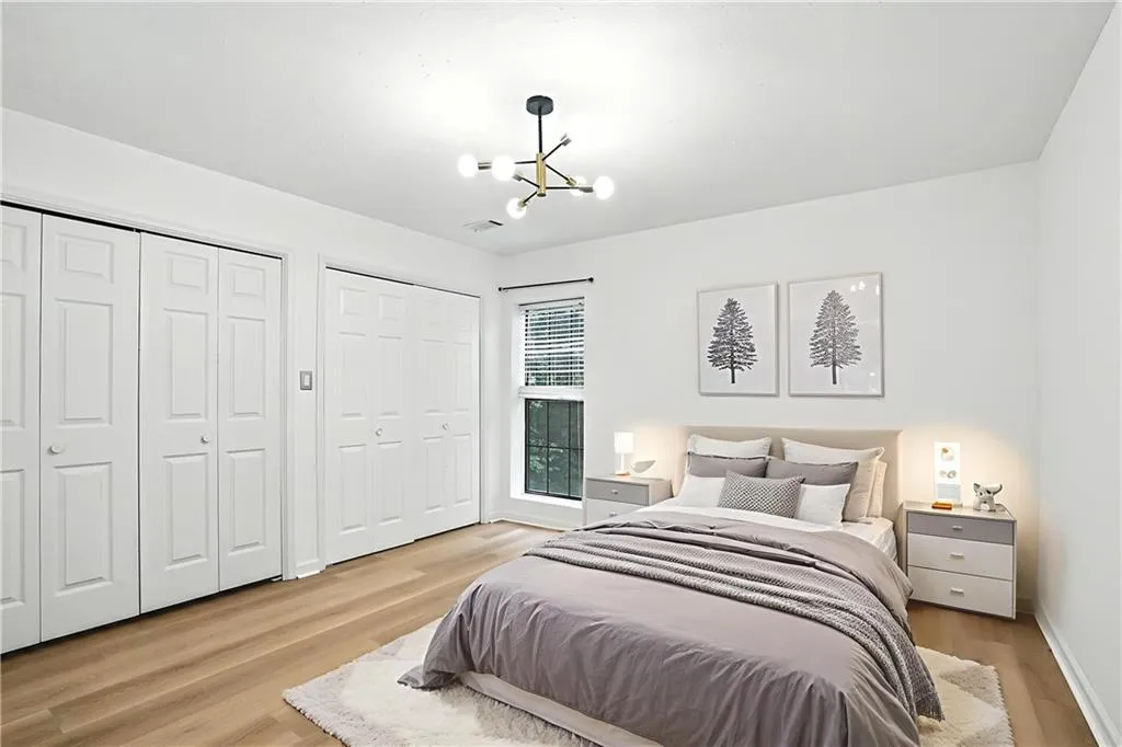 Bedroom featuring two closets, light wood finished floors, and a chandelier