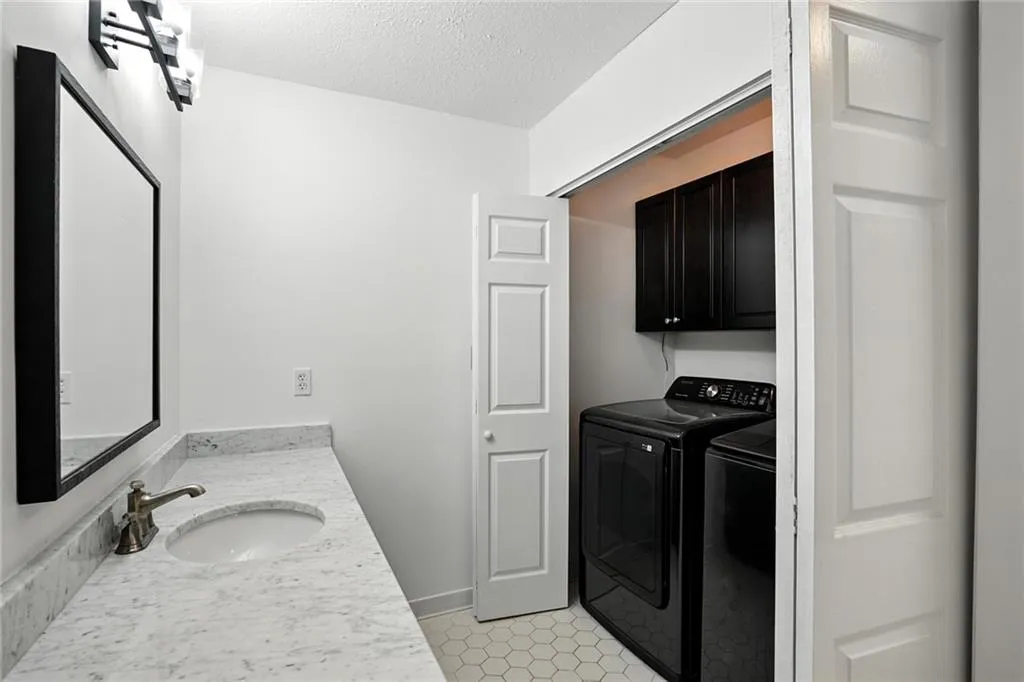 Washroom with cabinet space, washer and dryer, a textured ceiling, and light tile patterned floors